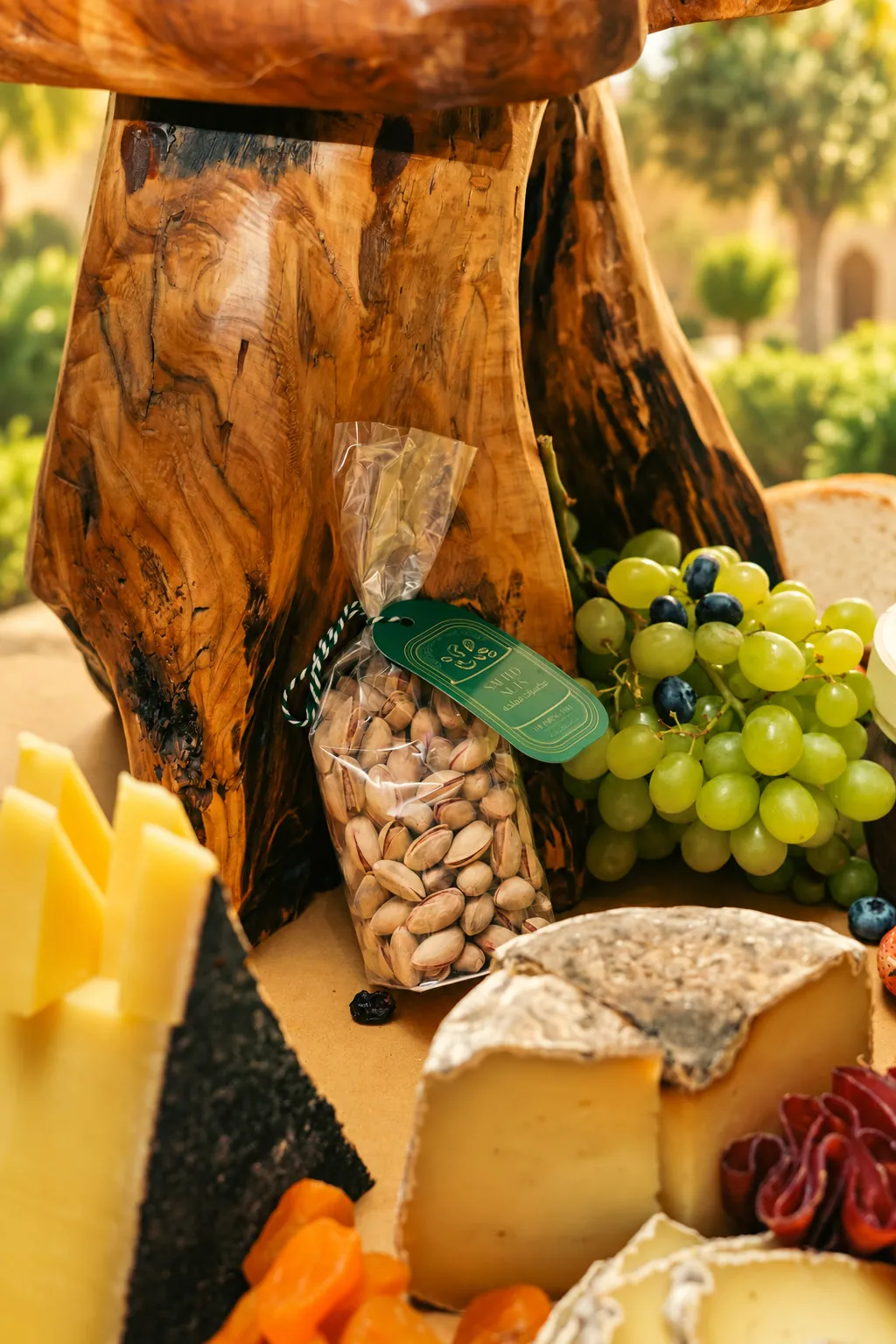 Nut mixes beside grapes and cheese on a wooden stand