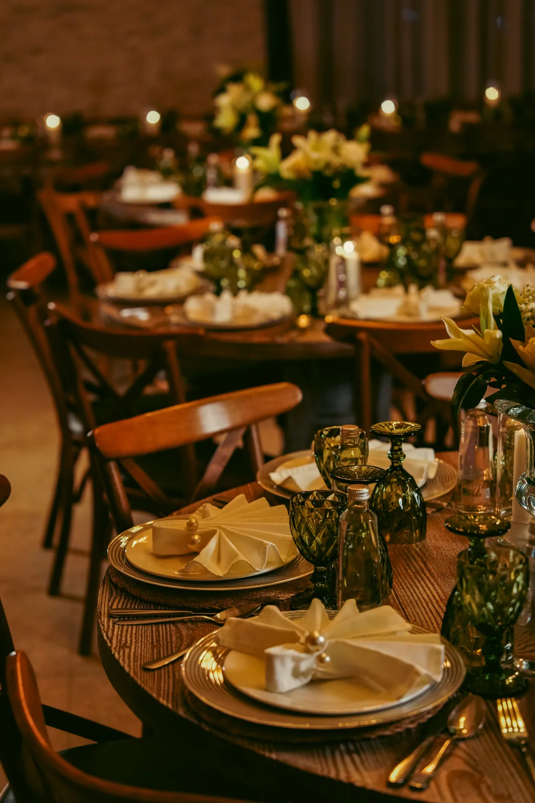 A Mirsam wedding setting with green glassware, folded pearl napkins and white flowers
